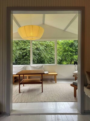 A room with a wooden table, a bench, and a large window with a view of greenery. - Nature-rich 60s holiday home by Isefjord (Jægerspris)