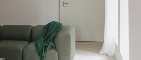 Un salon minimaliste avec un canapé, une porte et une fenêtre.