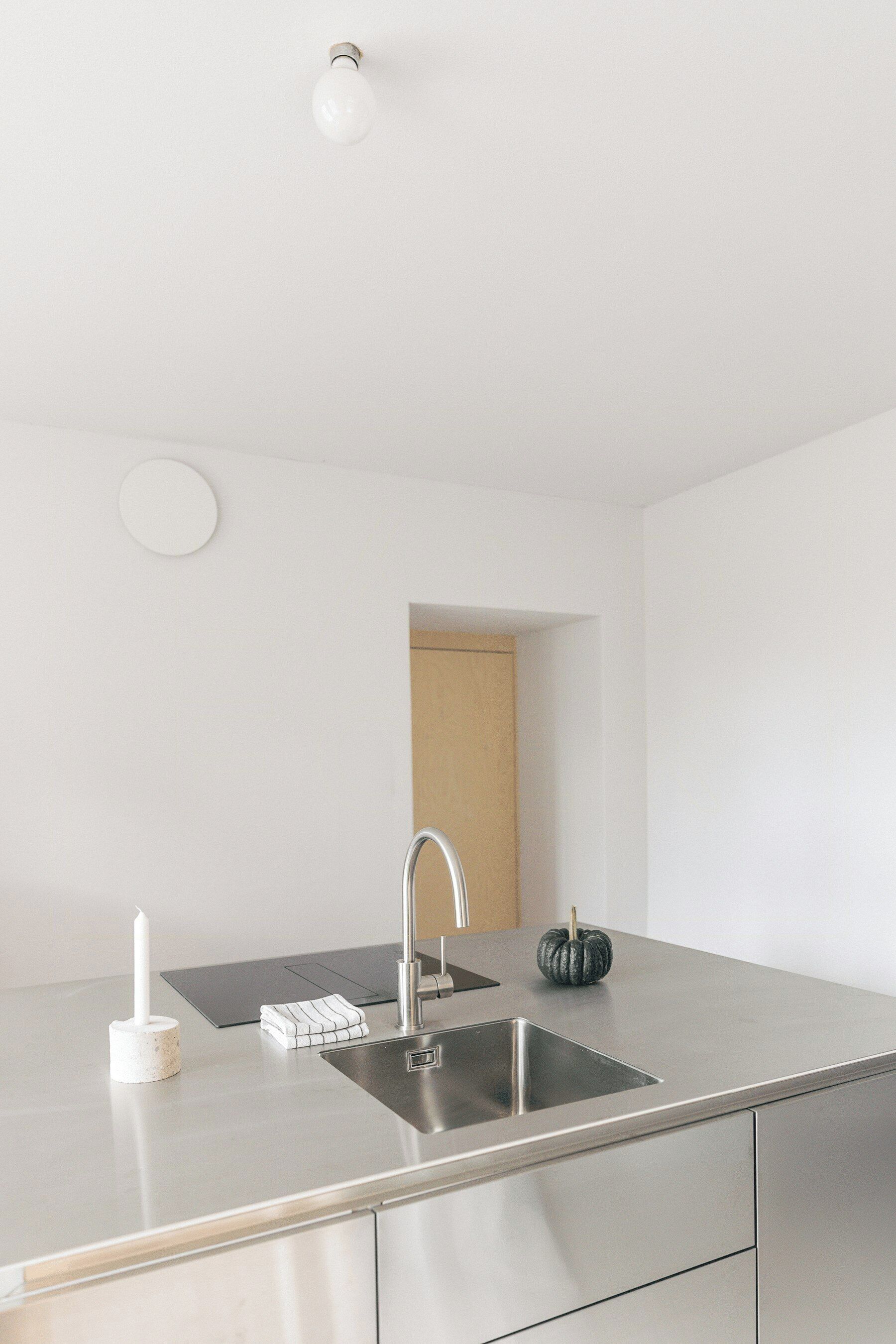 Een moderne keuken met een roestvrijstalen spoelbak, een witte kandelaar en een kleine pompoen decoratie.