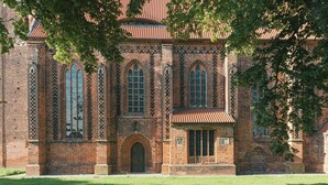 Ein historisches Backsteingebäude mit Rundbogenfenstern und einem zentralen Eingang.