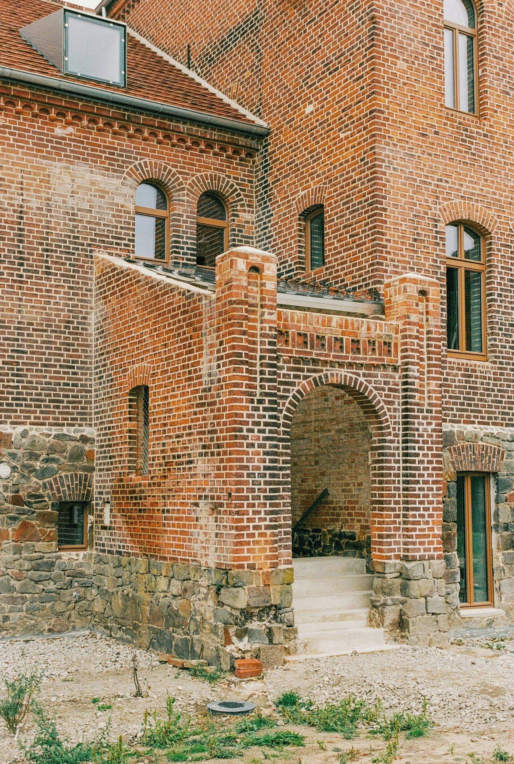 Een historisch gebouw van baksteen met gebogen ramen en een stenen ingang.