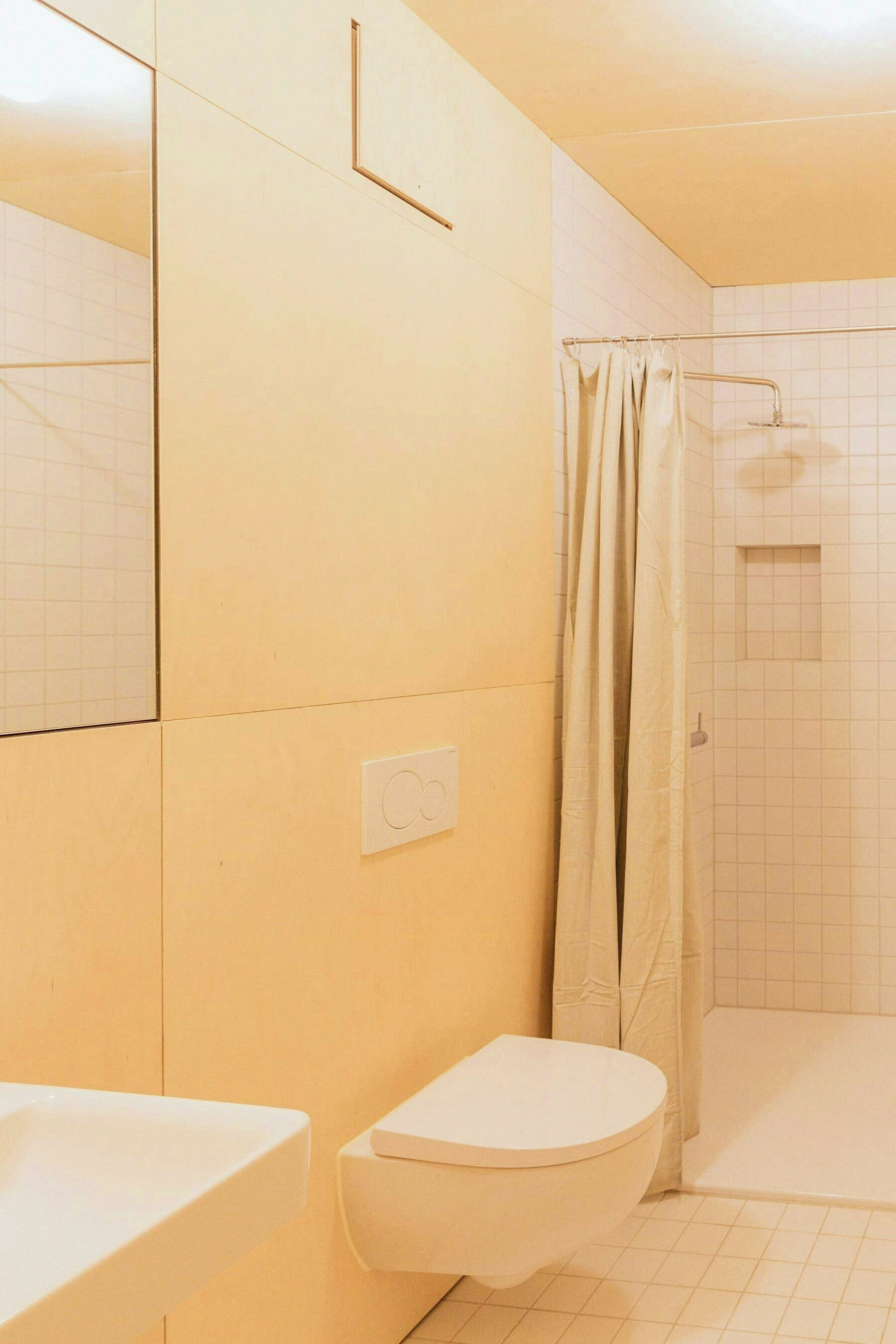 Une salle de bain équipée de toilettes, d’un lavabo, d’une douche et de murs carrelés.