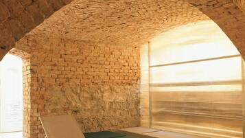 A room with a brick ceiling, a green pool table, and a white lounge chair.