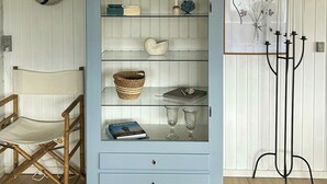 Ein Zimmer mit einem hellblauen Schrank, einem Regiestuhl, einem Spiegel und einem gerahmten Bild an der Wand.