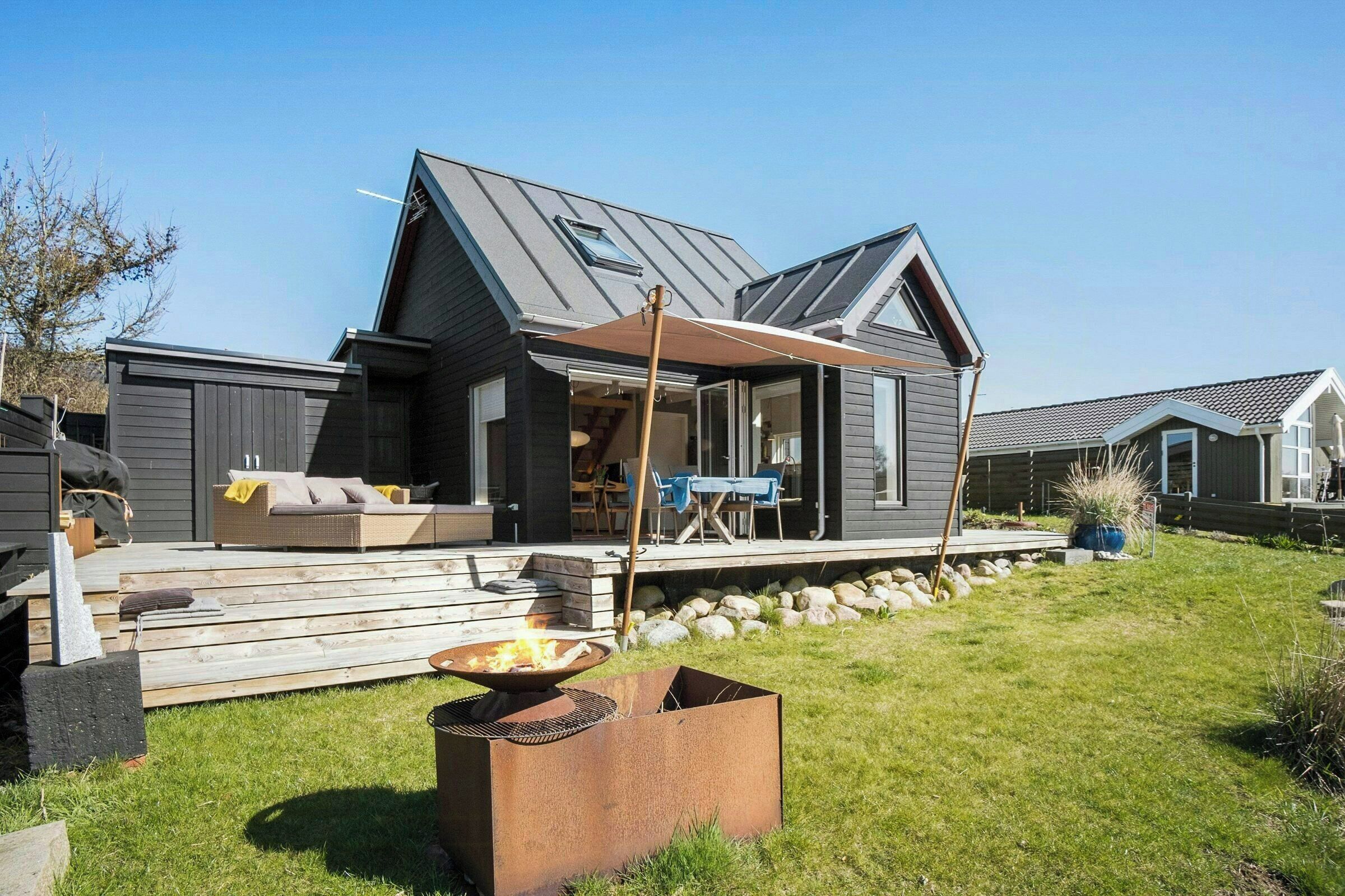 A modern house with a deck, a fire pit, and a covered patio area.