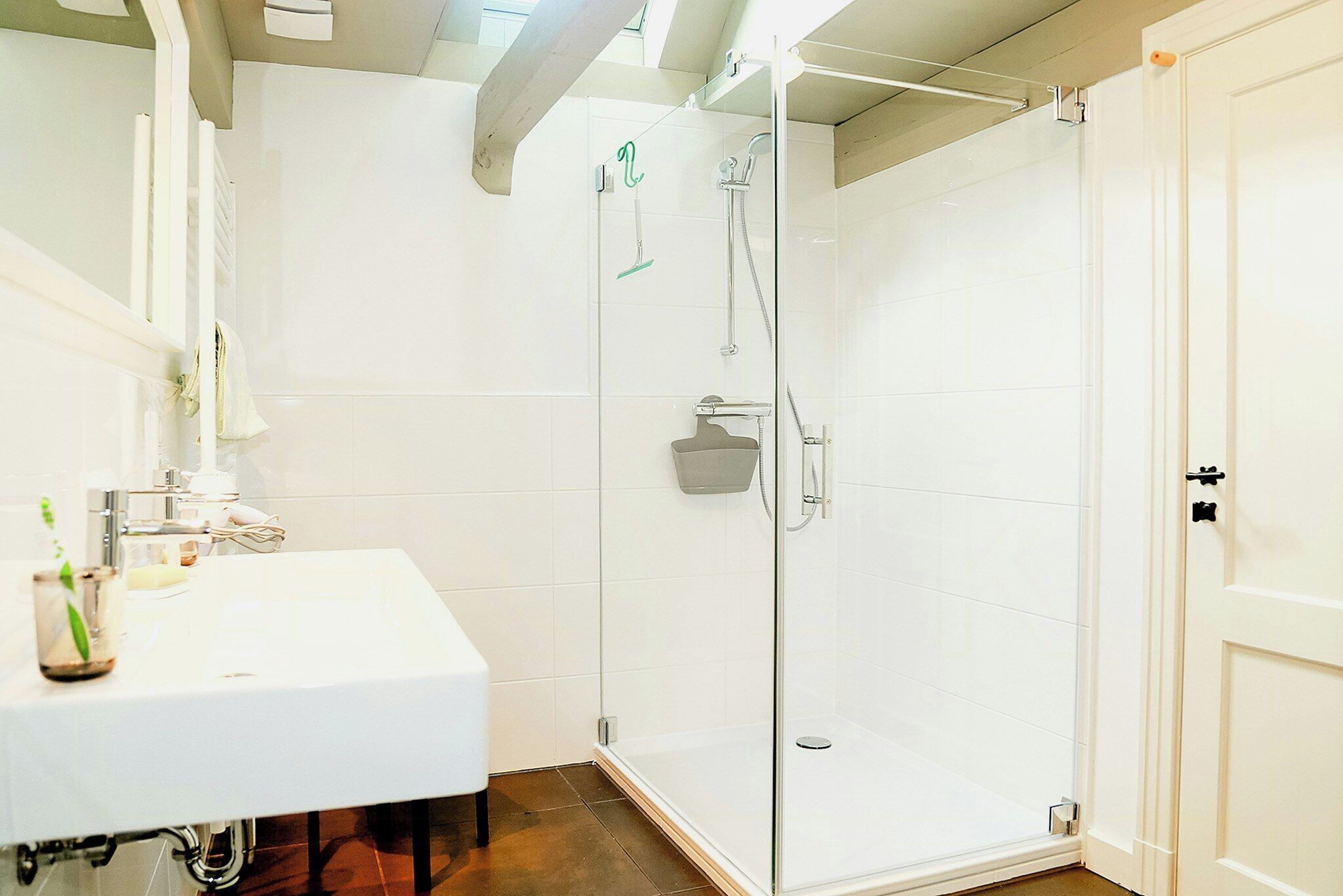 A bathroom with a white sink, a glass shower enclosure, and a white door.
