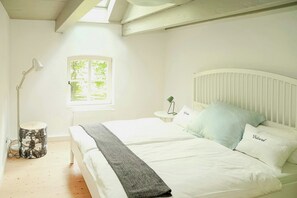 Ein Schlafzimmer mit Bett, Nachttisch, Lampe und Fenster.