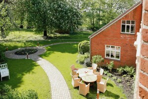 Ein Ziegelhaus mit Garten, einem gepflasterten Weg und Gartenmöbeln.