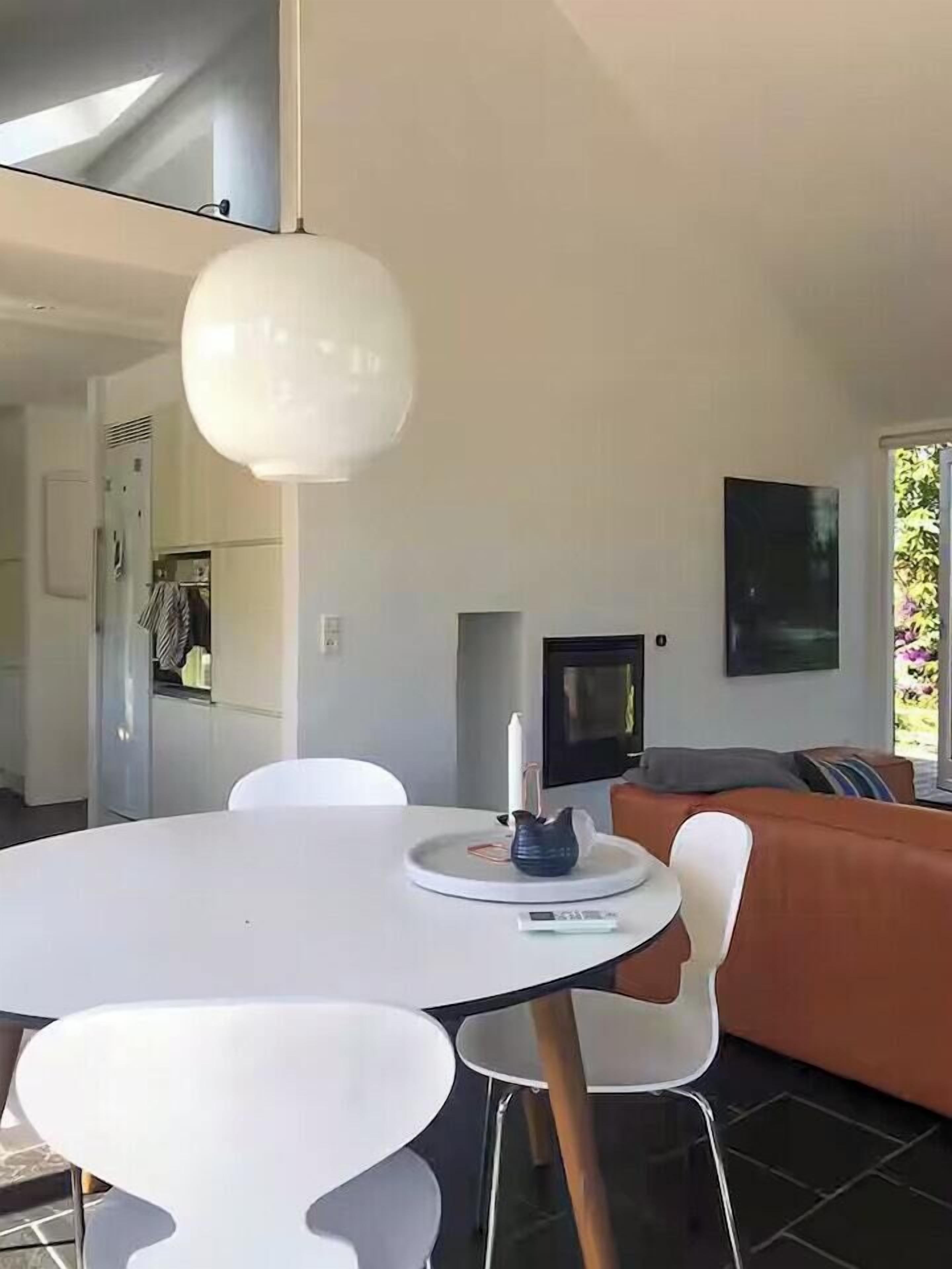 Ein modernes Wohnzimmer mit einem weißen Esstisch, einer Couch und einem Fernseher.