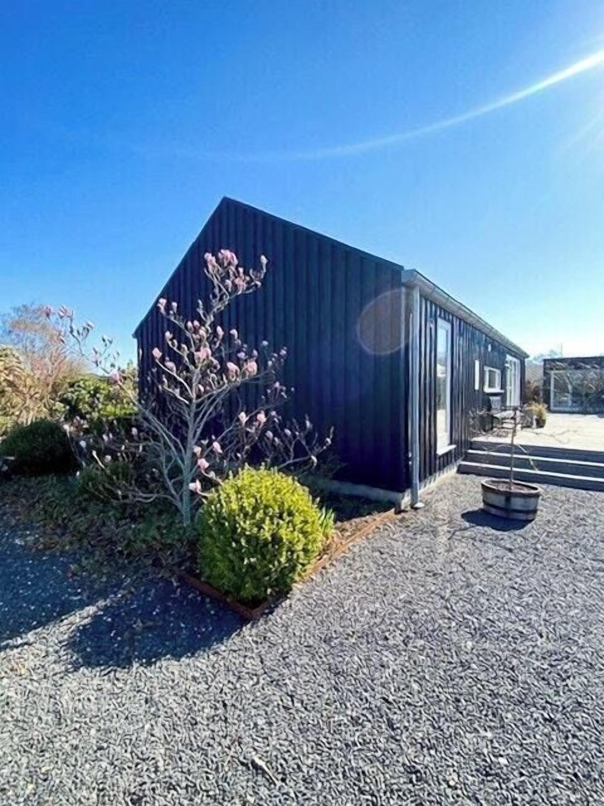 Un bâtiment moderne à l’extérieur sombre, doté d’une petite entrée et d’une allée gravillonnée.