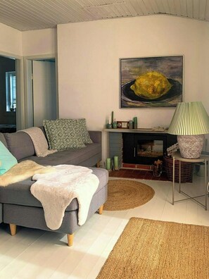 Ein modernes Wohnzimmer mit grauem Sofa, Kamin, Gemälde und Lampe.