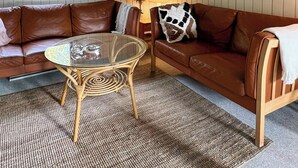 Una habitación acogedora con un sofá de cuero marrón, una mesa de vidrio y una lámpara.
