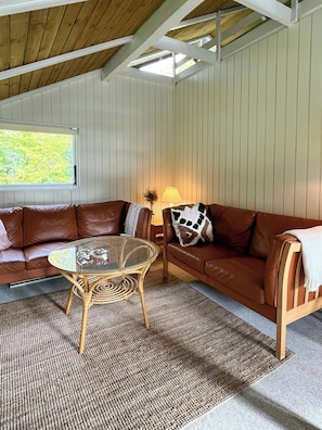 Ein gemütliches Zimmer mit einem braunen Ledersofa, einem Glastisch und einer Lampe.