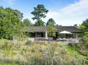 A modern house with a patio, surrounded by a garden and a wooden fence. - Design-led nature retreat, near Hornbæk beach (hornbæk)