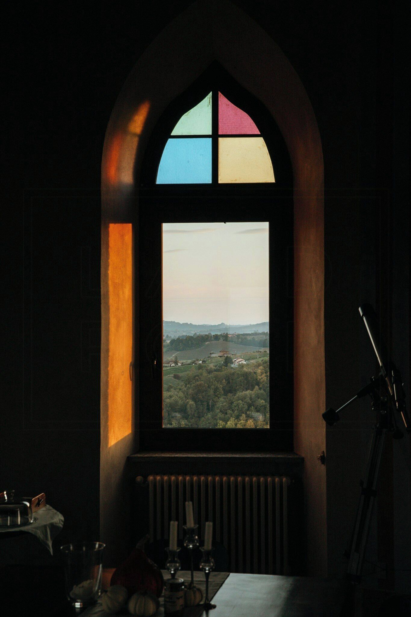 A room with a large arched window, a radiator, and a table with various items.