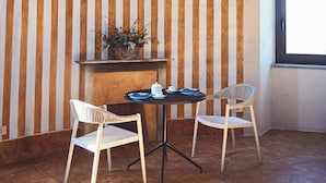 A room with striped walls, a table with chairs, a hanging light fixture, and a window. - Historic tower with Monferrato views (Terrugia)