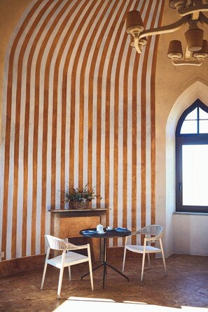 A room with striped walls, a table with chairs, a hanging light fixture, and a window.