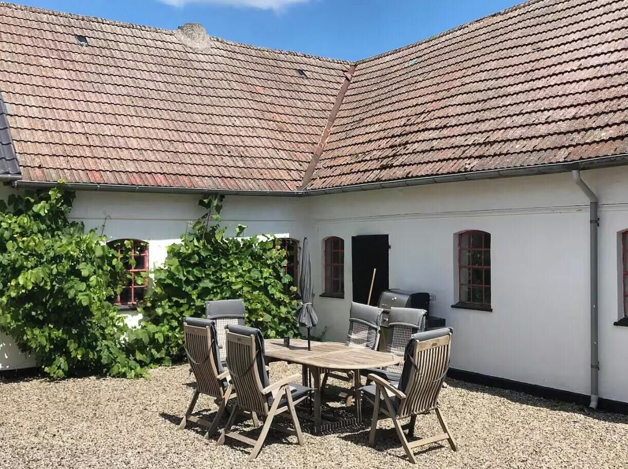 Een binnenplaats met een wit gebouw, een tafel met stoelen en een barbecue.