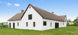Un bâtiment blanc doté d’un toit à forte pente, de nombreuses fenêtres et d’une cheminée.