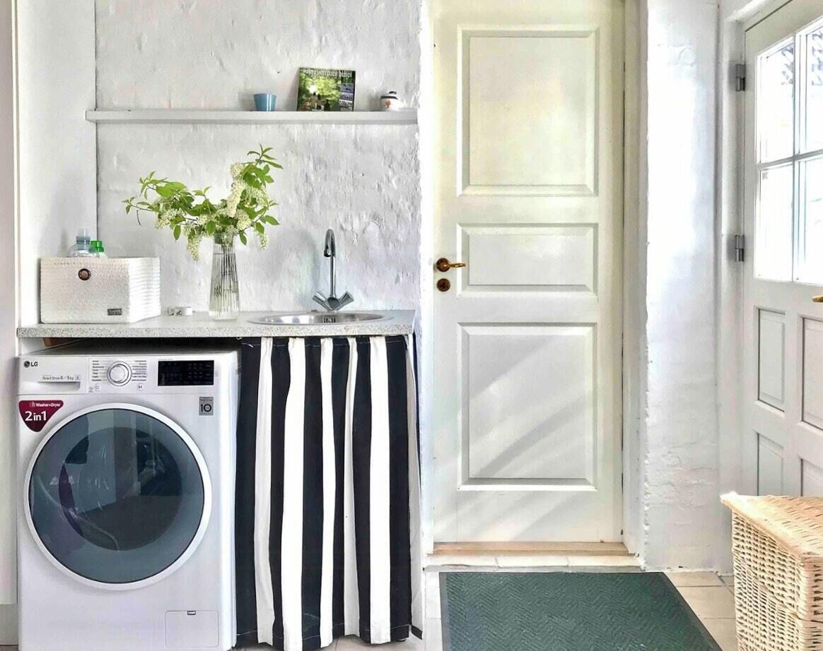 Un espace buanderie comprenant un lave-linge, un évier et une porte.