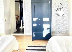 A room with a door, a bed, a rug, and a wall-mounted light fixture.