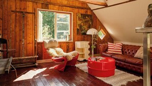 A cozy room with wooden walls, a red chair, a brown leather sofa, and a red coffee table.