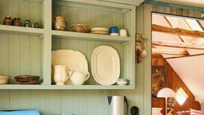 A kitchen with wooden cabinets, a blue suitcase, and a coffee maker.