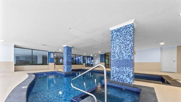 An indoor swimming pool with tiled walls and a metal ladder.