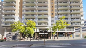 A multi-story hotel with a modern architectural design, featuring balconies on each floor and a central entrance.