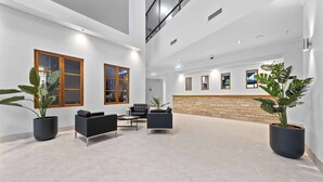 A spacious lobby with a high ceiling, large windows, and a stone accent wall.