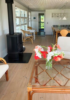 Ein modernes Wohnzimmer mit Kaminofen, Essbereich mit Tisch und Stühlen sowie einer Couch.