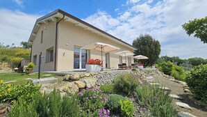 Una casa moderna con patio, area salotto esterna e giardino.
