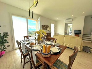 A dining area with a table set for four, chairs, a vase with flowers, and a view of the outdoors. - Panoramic villa in the Lucca hills (Capannori)