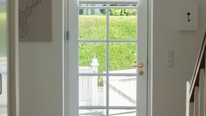 A white door with a window, a ceiling fan, and a wall-mounted light switch. - House in Rørvig Park filled with charm (Bysted)