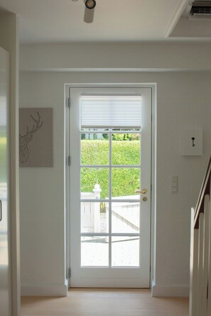 A white door with a window, a ceiling fan, and a wall-mounted light switch. - House in Rørvig Park filled with charm (Bysted)