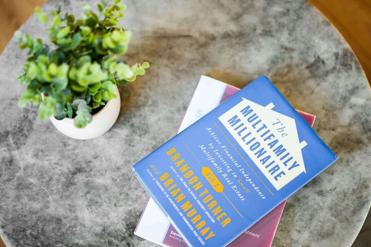 A book titled 'The Millionaire Multiplier' by Brian Murray on a marble surface.