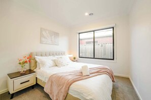 Une chambre à coucher avec un lit, une table de chevet et une fenêtre.