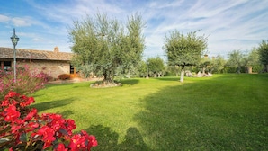 A well-maintained lawn, a stone building, and trees in a garden setting. - Apartment with views of Lake Trasimeno (Castiglione del Lago)