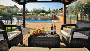 An outdoor seating area with wicker furniture, a pool, and a fruit basket. - Apartment with views of Lake Trasimeno (Castiglione del Lago)