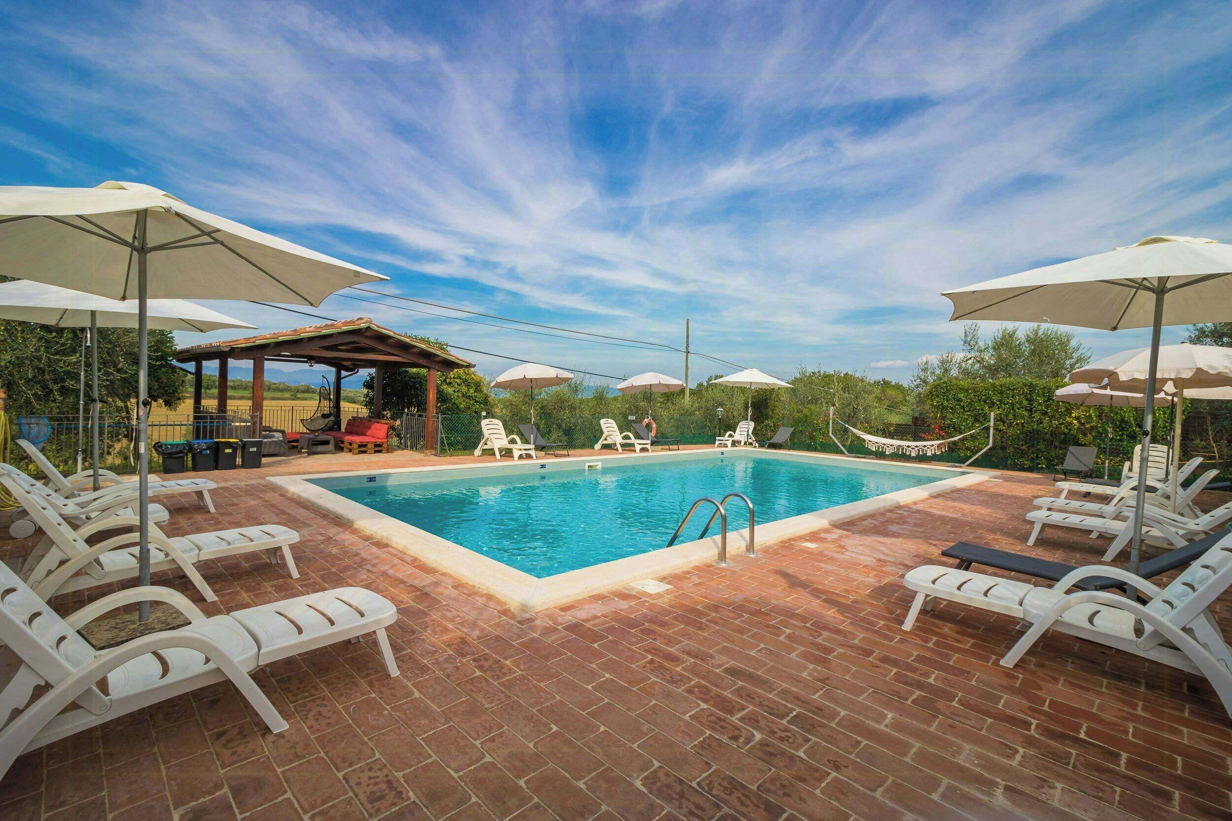 Ein Pool mit Liegestühlen und Sonnenschirmen, umgeben von einer Pflasterterrasse.
