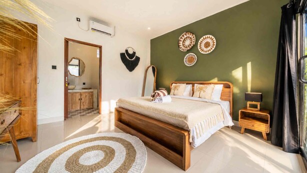 Un dormitorio con cama de madera, alfombra redonda, mesita de noche y decoración en la pared.