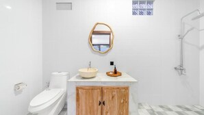 A modern bathroom with a toilet, sink, shower, and wooden cabinet. - Bella Vita Villa (Kerobokan)