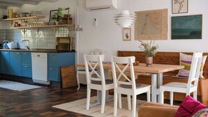 Un comedor con una mesa de madera y sillas blancas, una cocina con armarios azules y un mapa en la pared.