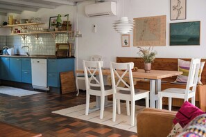 Ein Essbereich mit Holztisch und weißen Stühlen, eine Küche mit blauen Schränken und eine Karte an der Wand.