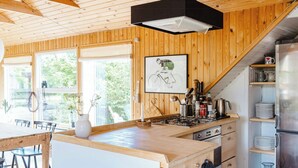 A wooden interior with a kitchen island, dining area, and a staircase leading to a loft. - Close to beach, forest and bike trails (Grenå)