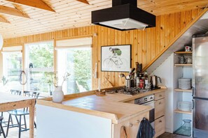 A wooden interior with a kitchen island, dining area, and a staircase leading to a loft. - Close to beach, forest and bike trails (Grenå)