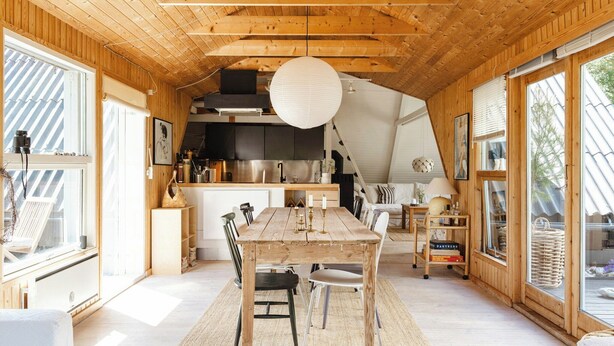A wooden interior with a dining table, chairs, and a kitchen area. - Close to beach, forest and bike trails (Grenå)
