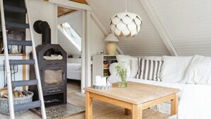 A cozy room with a wooden table, white sofa, and a fireplace. - Close to beach, forest and bike trails (Grenå)