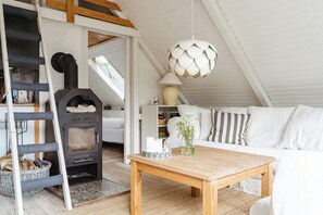 A cozy room with a wooden table, white sofa, and a fireplace. - Close to beach, forest and bike trails (Grenå)