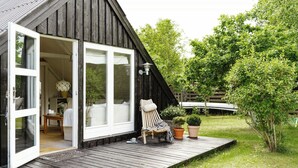 A wooden cabin with a deck, a chair, and potted plants. - Close to beach, forest and bike trails (Grenå)